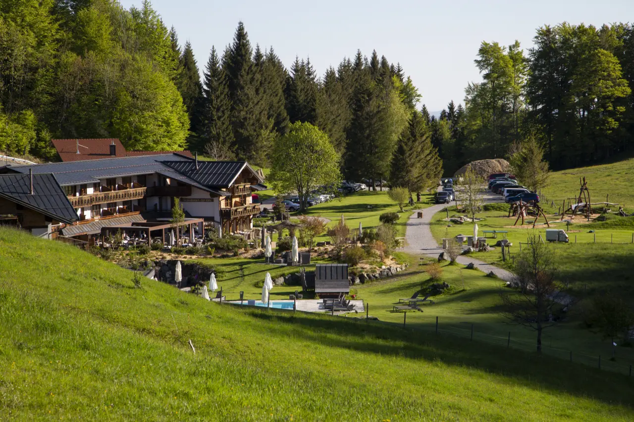 Panoramablick auf das Hotel Schlossanger Alp mit traditioneller Architektur, Aussenpool und grünen Hügeln in den Alpen.