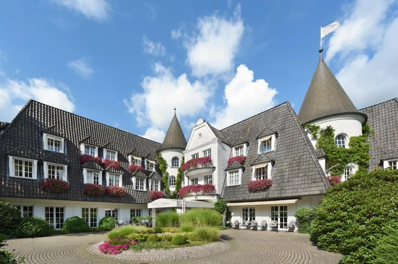 Charmante Aussenansicht des Landhaus Wachtelhof mit blühenden Blumenkästen und gepflegtem Eingangsbereich unter blauem Himmel.