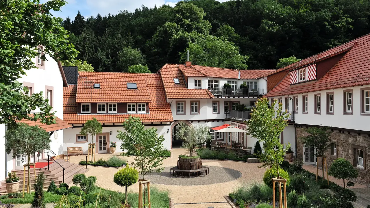 Charmantes Relais & Châteaux Hardenberg BurgHotel mit gepflegtem Innenhof und grüner Waldkulisse.