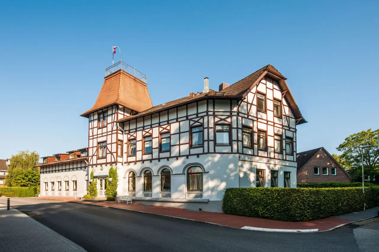 Aussenansicht des Hotel Birke mit traditioneller Fachwerkarchitektur, umgeben von gepflegtem Gruen unter blauem Himmel.