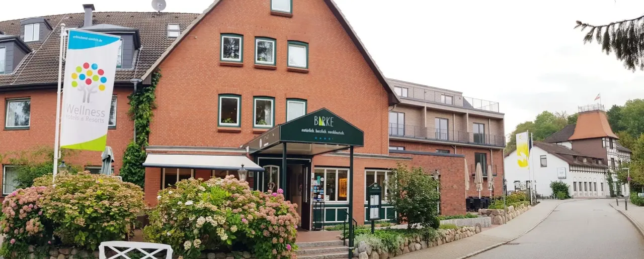 Aussenansicht des Hotel Birke in Kiel mit rotem Backstein, grünen Fenstern und 'Wellness Hotels & Resorts' Flagge.
