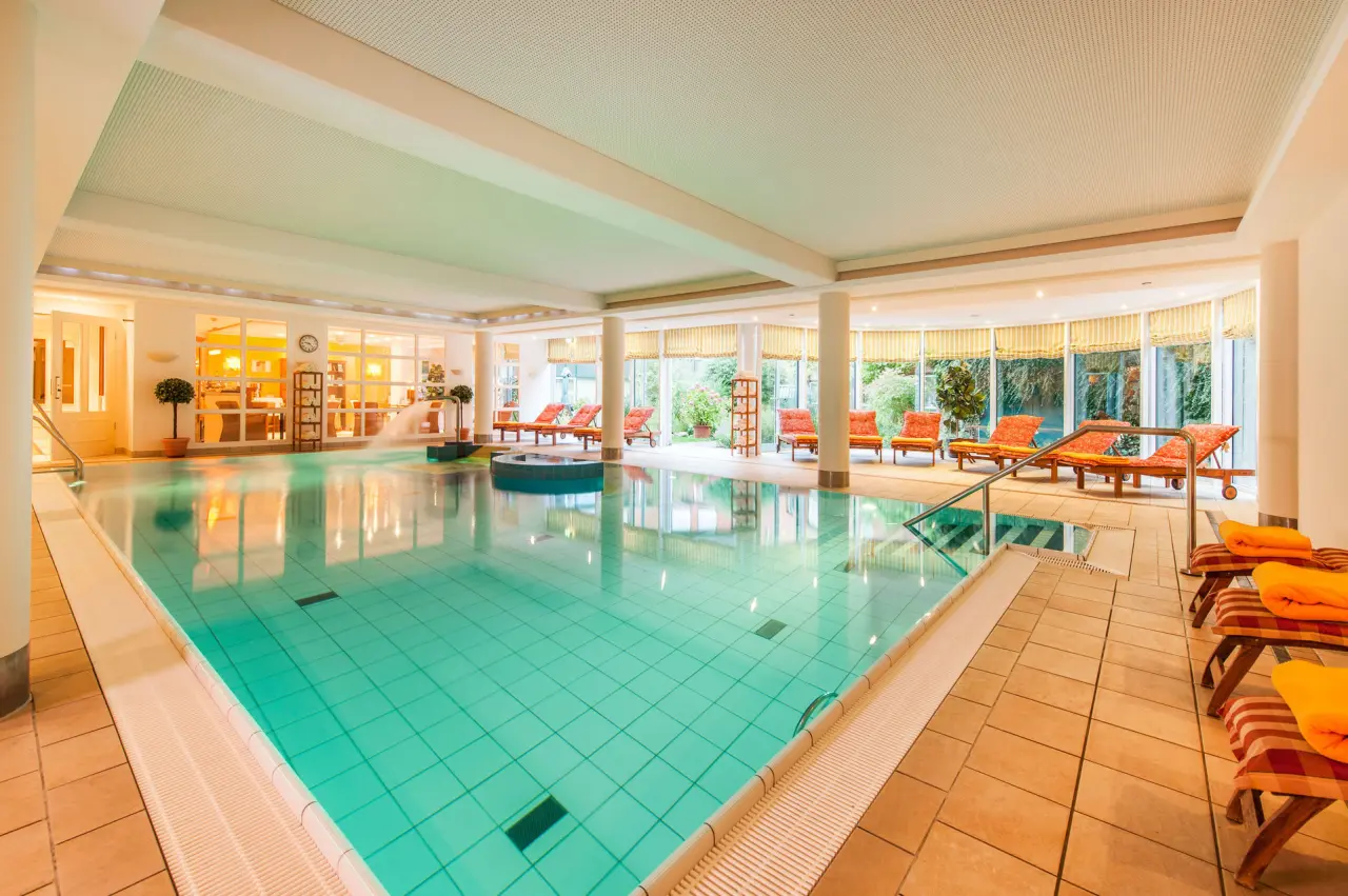Grosszügiger Innenpoolbereich mit Whirlpool, Liegestühlen und Tageslicht im Hotel Birke