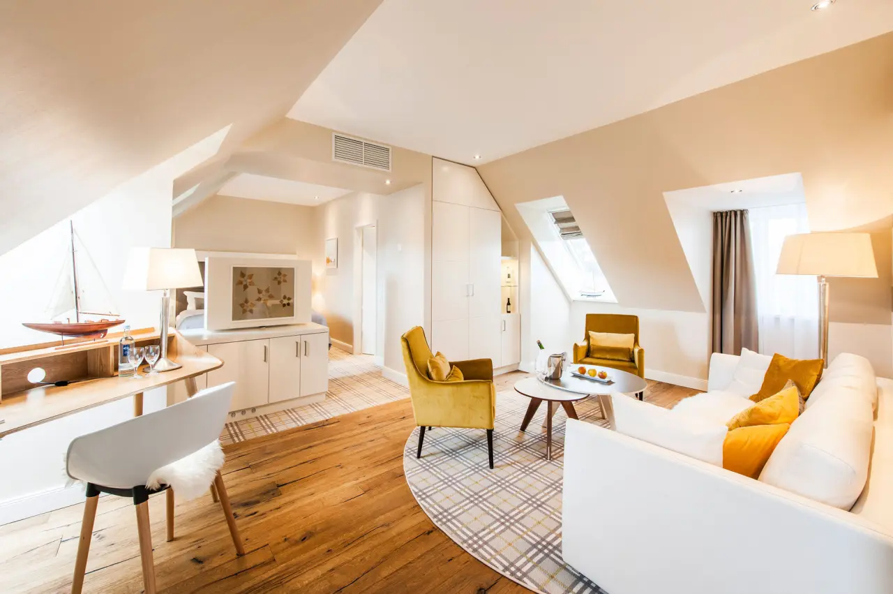 Geräumige Dachgeschoss-Suite im Hotel Birke mit Wohnbereich, Schreibtisch und gemütlichen Sesseln in warmen Farben.