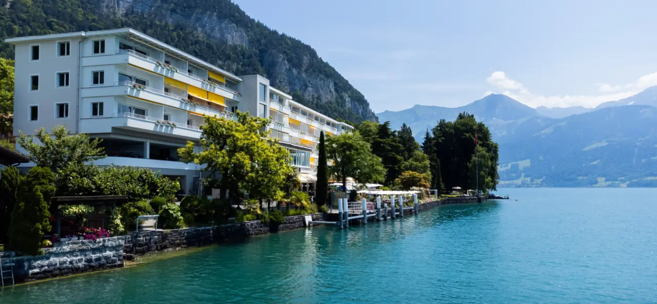 Aussenansicht des BEATUS Wellness- & Spa-Hotels am Thunersee mit Bergpanorama und Bootssteg.
