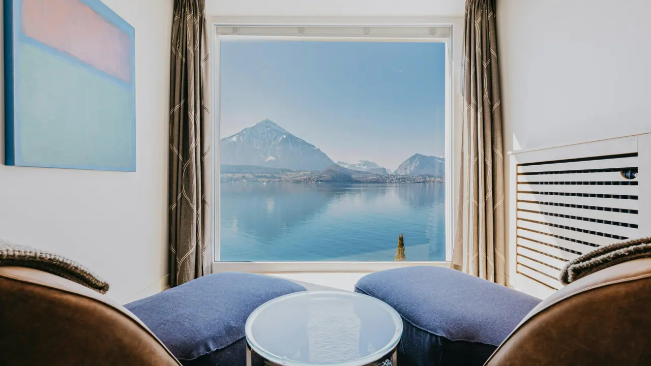 Gemütlicher Sitzbereich im BEATUS Wellness- & Spa-Hotel mit Panoramablick auf den Thunersee und die Schweizer Alpen.