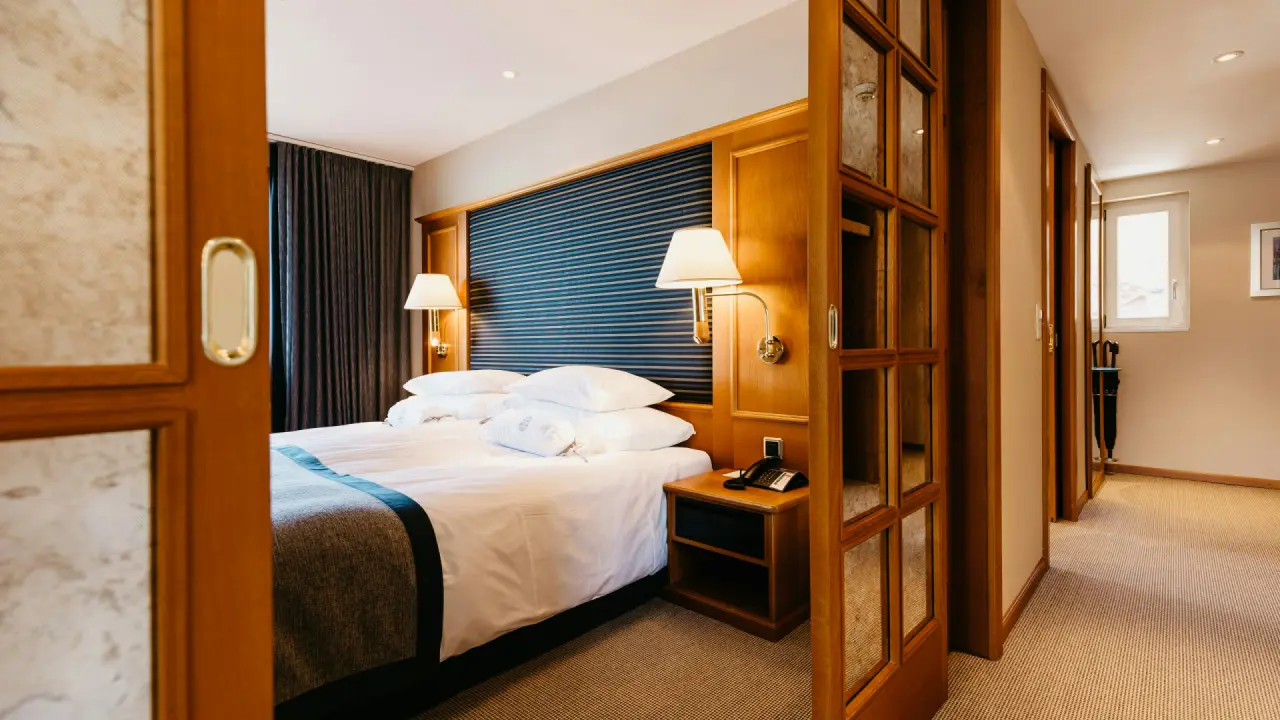 Komfortables Doppelzimmer mit Holzelementen und gemütlichem Bett im BEATUS Wellness- & Spa-Hotel.