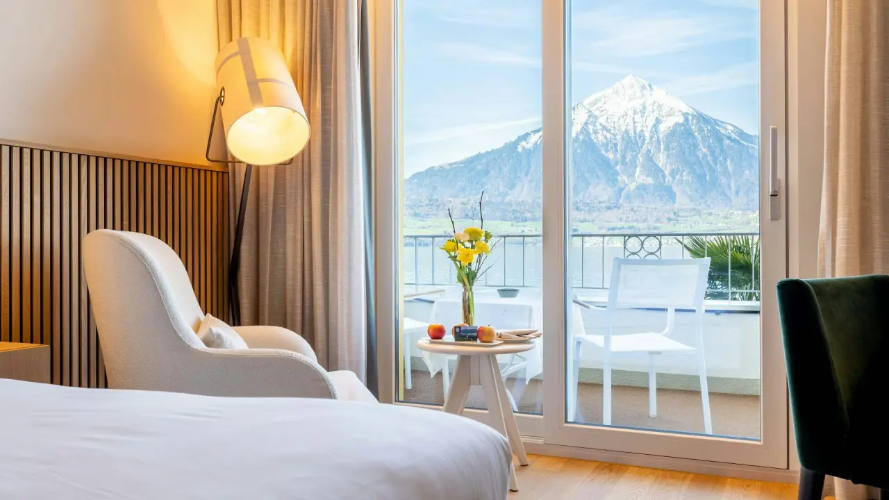 Geräumiges Hotelzimmer im BEATUS Wellness- & Spa-Hotel mit Balkon und Panoramablick auf den Thunersee und die Alpen.