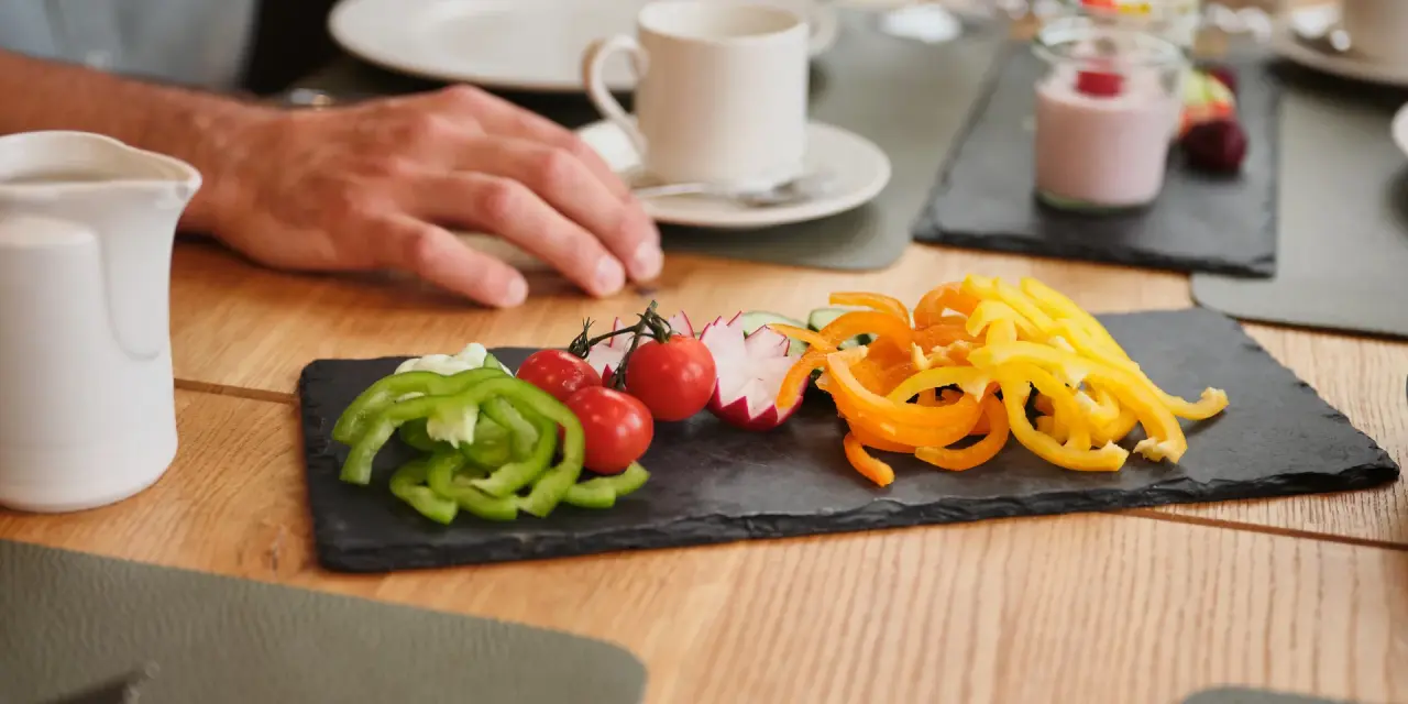 Frisches Gemüse wie Paprika, Tomaten und Radieschen auf Schieferplatte beim Frühstück im Sporthotel Wagrain.