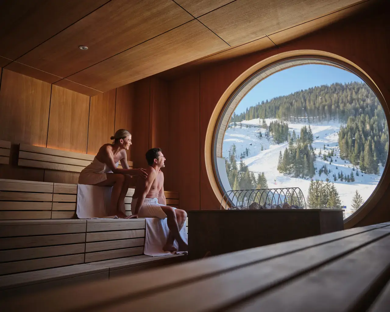 Modernes Saunaerlebnis im Sporthotel Wagrain mit Panoramablick auf die verschneite Berglandschaft und Skipisten.