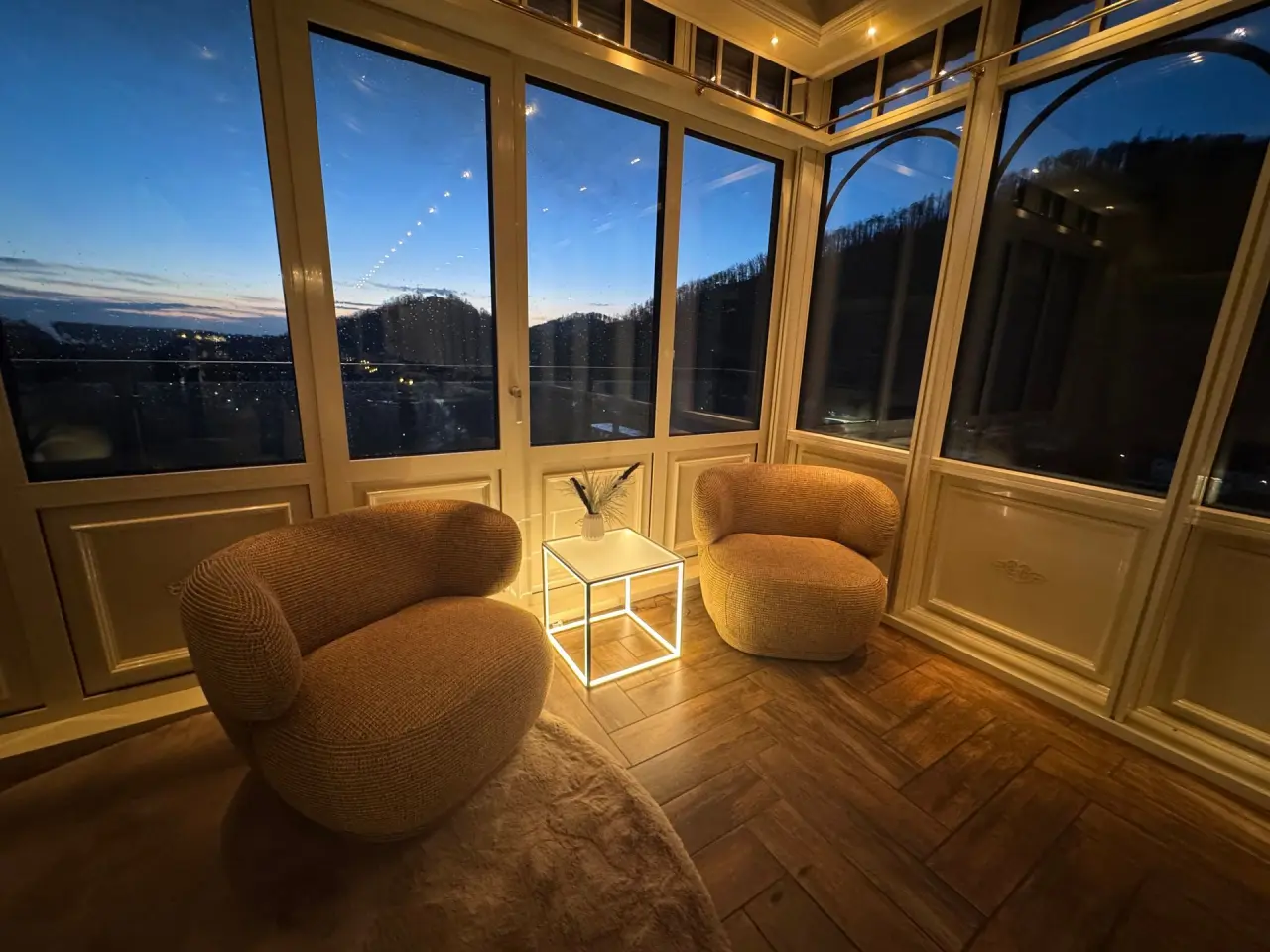 Gemütlicher Lounge-Bereich im Revita Wellnesshotel bei Dämmerung mit bequemen Sesseln, leuchtendem Tisch und Blick ins Tal.