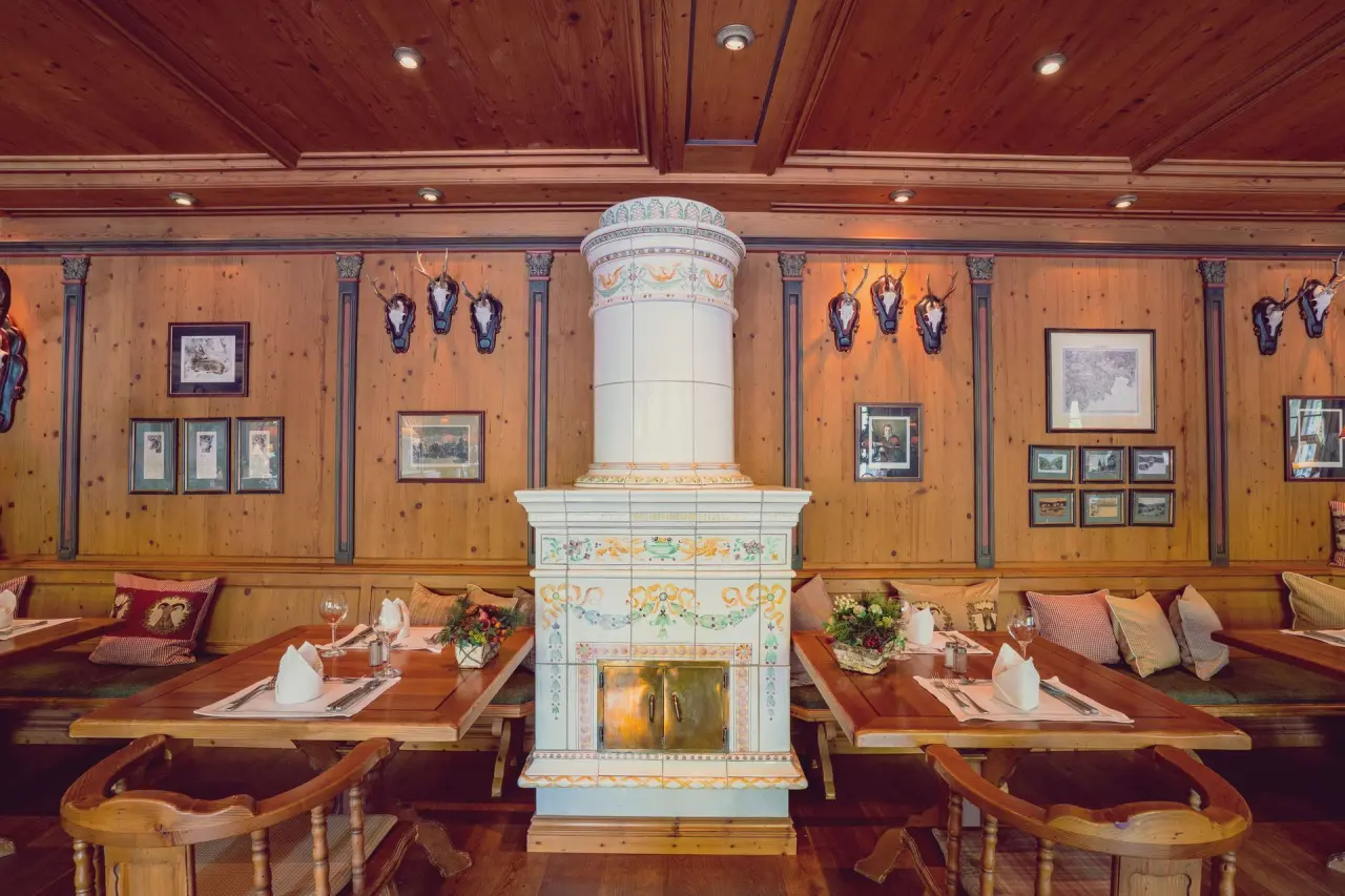 Gemütliches Restaurant im Revita Wellnesshotel mit traditioneller Holzvertäfelung, Kachelofen und festlich gedeckten Tischen.