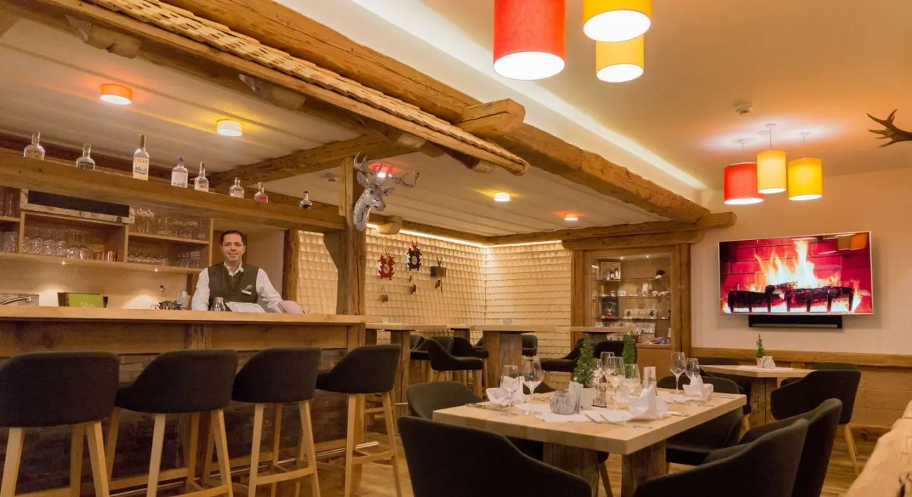Gemütliches Restaurant und Bar im Naturparkhotel Grüner Baum mit traditionellem Holzdesign, gedeckten Tischen und Kamin-TV.