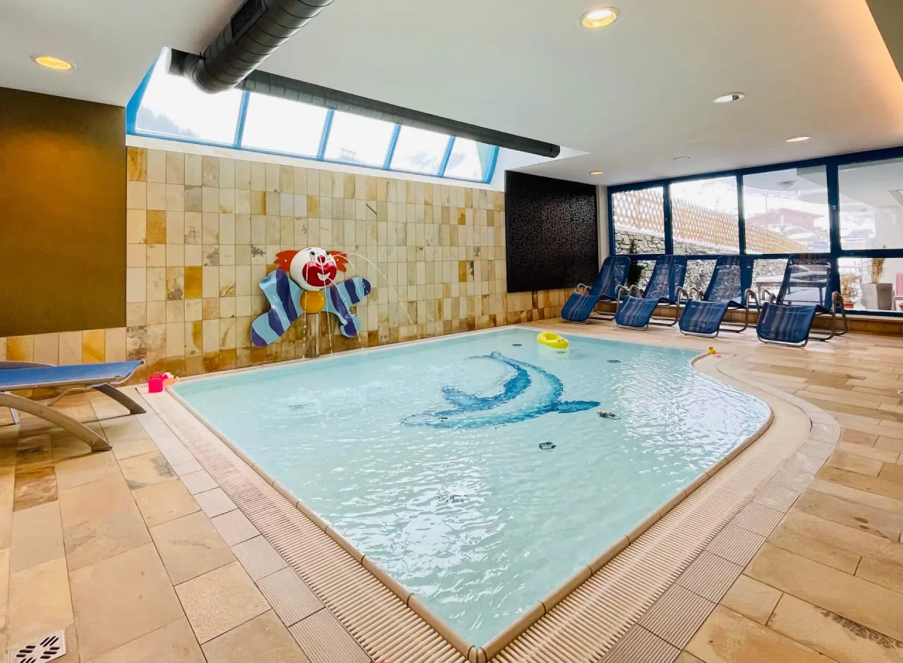 Familienfreundlicher Innenpool mit Clown-Wasserspiel und Delfin-Mosaik im Wellness- & Familienhotel Egger.