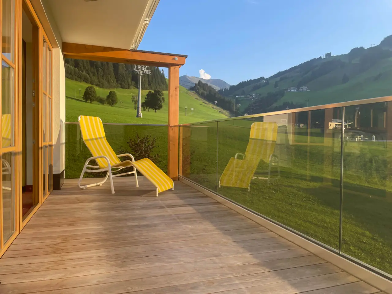 Sonnenverwöhnter Balkon mit Liegestuhl und Panoramablick auf die Berge im Wellness- & Familienhotel Egger.