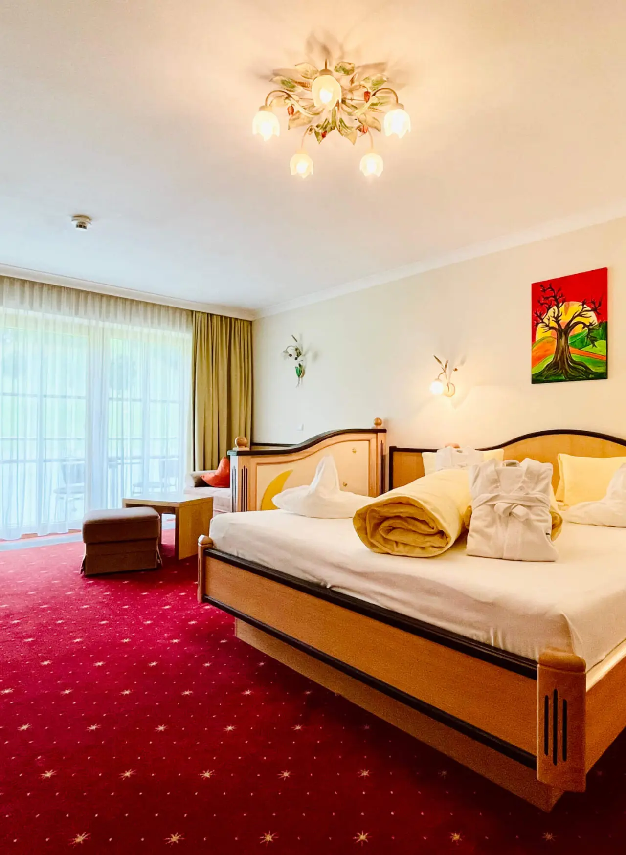 Gemütliches Doppelzimmer mit Balkon, Bademänteln und rotem Teppich im Wellness- & Familienhotel Egger.