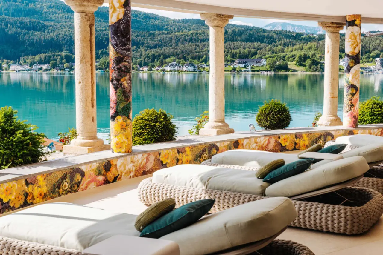 Luxuriöse Liegen auf der Seeterrasse des Hotel Schloss Seefels mit Blick auf den Wörthersee und die umliegenden Berge.