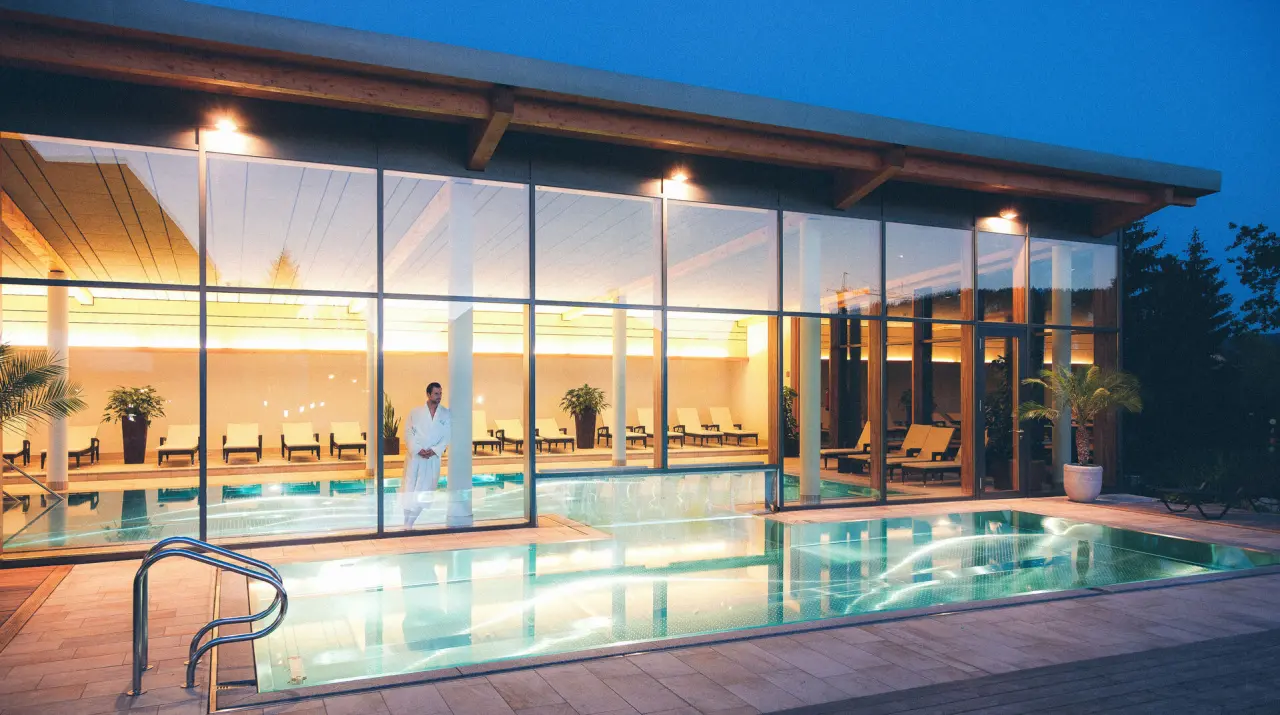 Modernes Schwimmbad mit Innen- und Aussenbereich bei Abenddämmerung im Hotel Eibl-Brunner.