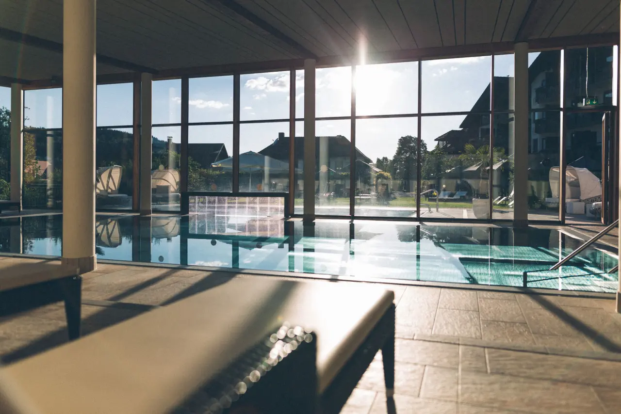Sonnendurchfluteter Indoor-Pool mit grossen Panoramafenstern und Liegebereich im Hotel Eibl-Brunner.