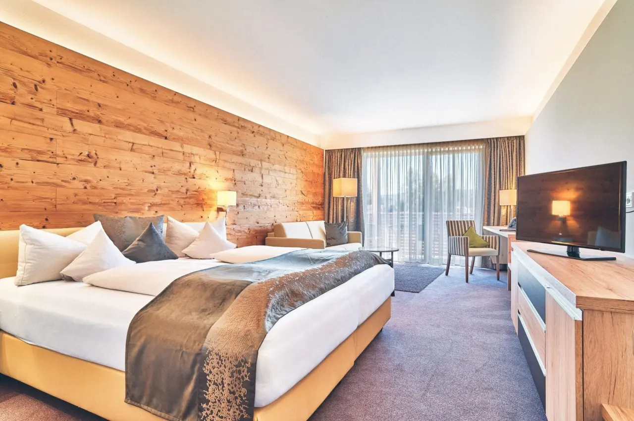 Geräumiges Doppelzimmer mit Holzwand, Balkon und gemütlicher Sitzecke im Hotel Eibl-Brunner.