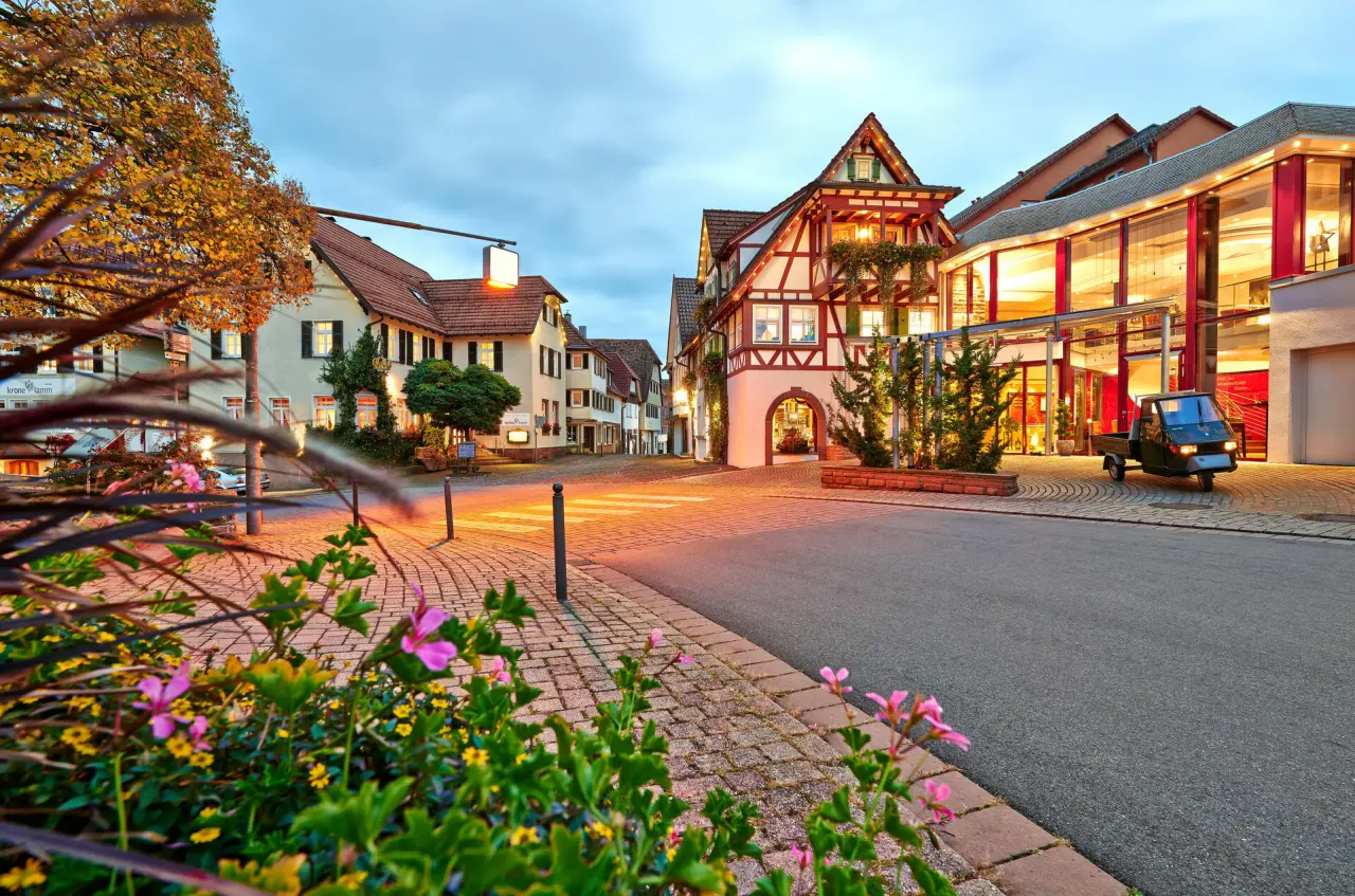 Abendliche Aussenansicht des Hotels Berlins KroneLamm mit beleuchteten Fachwerkhäusern und Dorfstrasse.