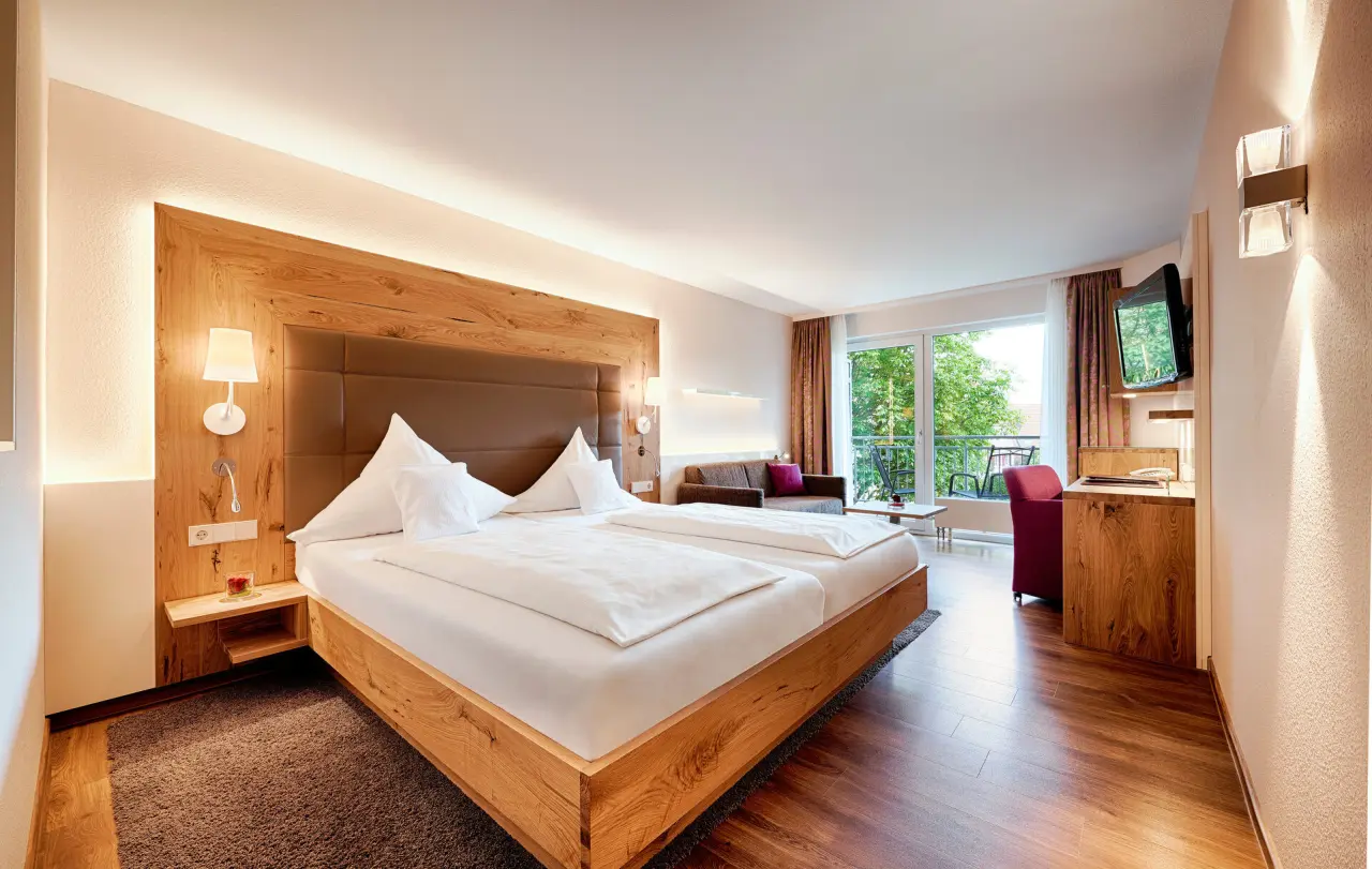 Komfortables Doppelzimmer mit Holzelementen, Balkon und Sitzbereich im Hotel Berlins KroneLamm.