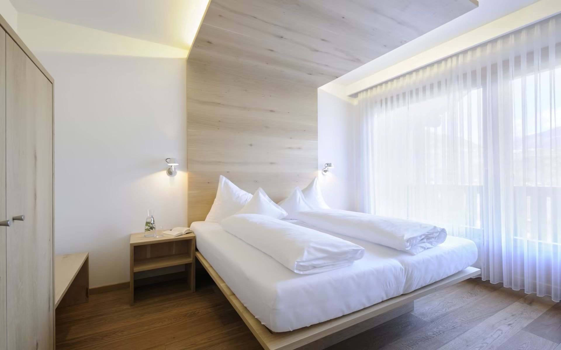 Bio- & Wellnesshotel PAZEIDER in Marling – Helles Doppelzimmer mit Holzelementen und Gardinen | Wellnesshotel Südtirol