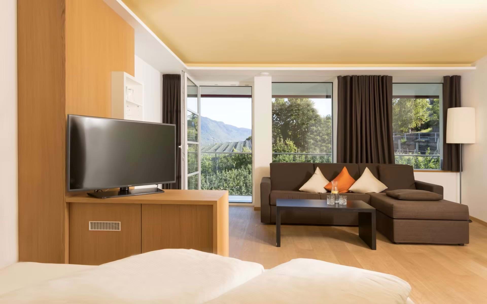 Bio- & Wellnesshotel PAZEIDER in Marling – Geräumige Suite mit Sofa und Blick ins Grüne | Wellnesshotel Südtirol