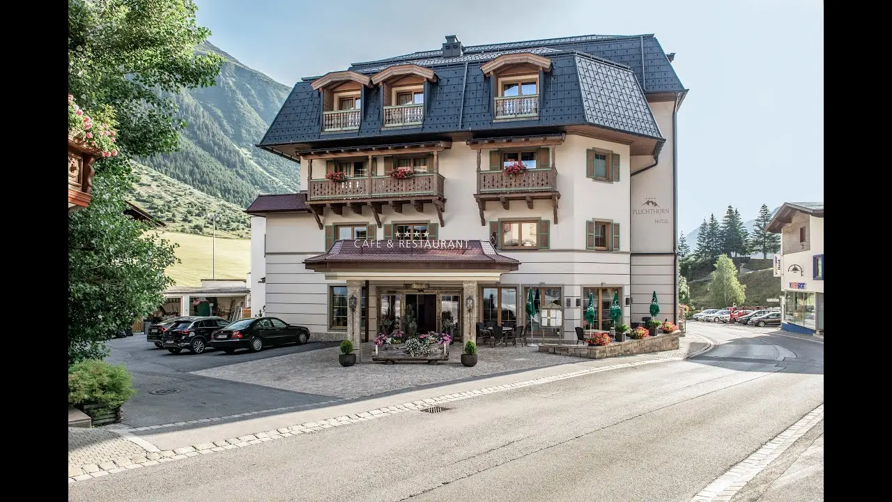 Traditionelles Alpenresort Fluchthorn mit Balkonen und Blumenkästen vor beeindruckender Bergkulisse in den Alpen.