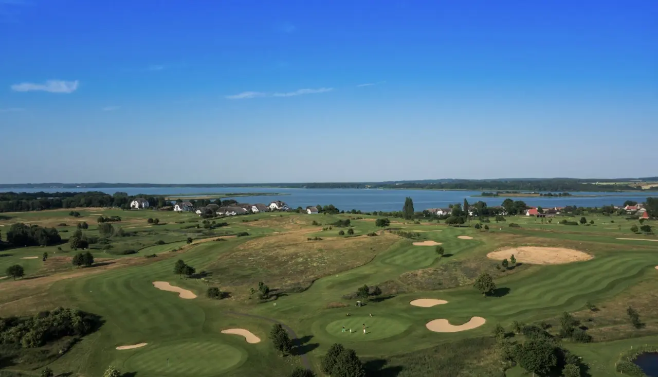 Luftaufnahme des weitläufigen Golfplatzes am Balmer See mit Hotelgebäuden und blauem Himmel im Balmer See - Hotel·Golf·Spa.