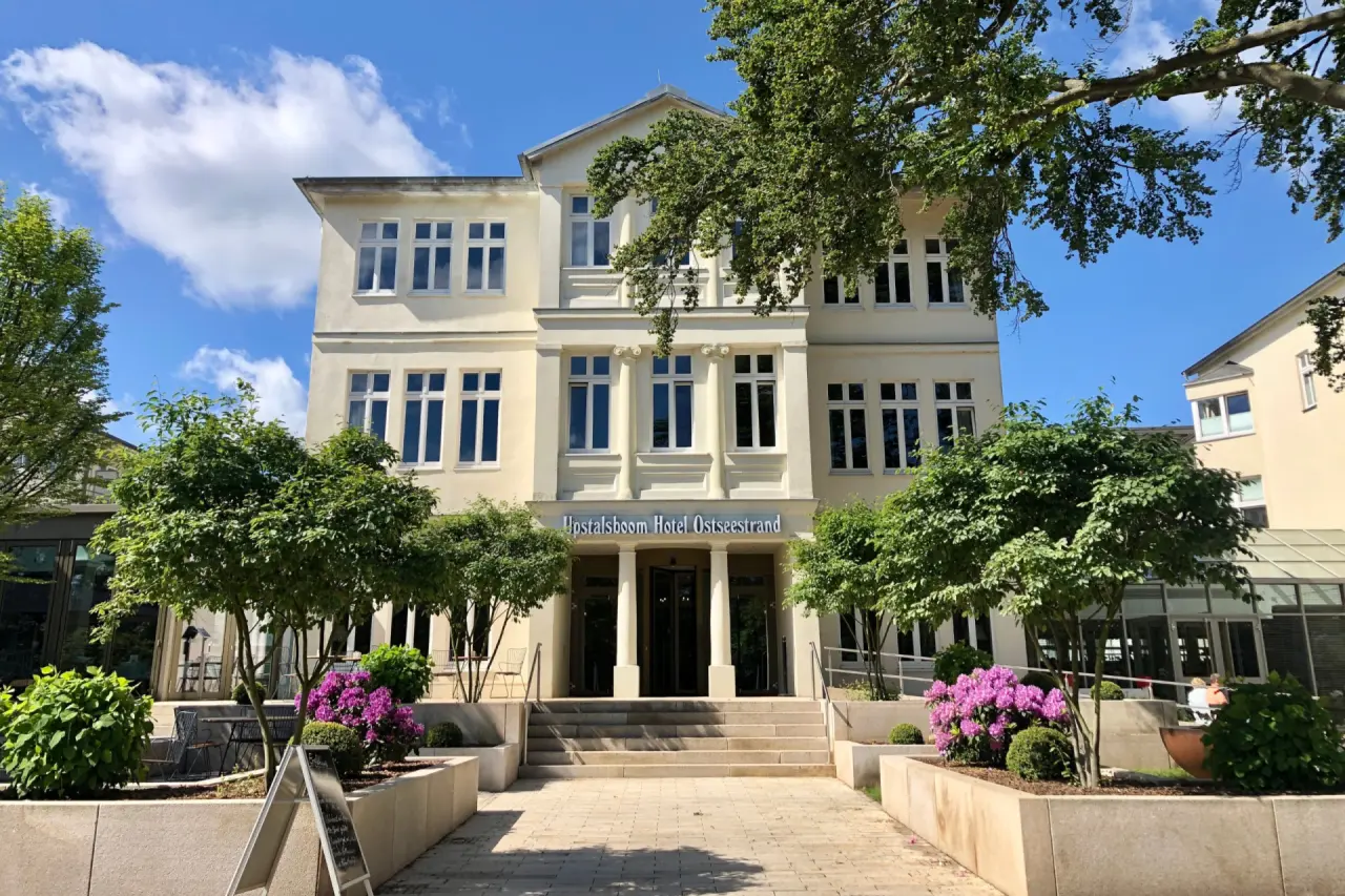 Aussenansicht des Upstalsboom Hotel Ostseestrand in Heringsdorf mit blühenden Pflanzen und blauem Himmel.
