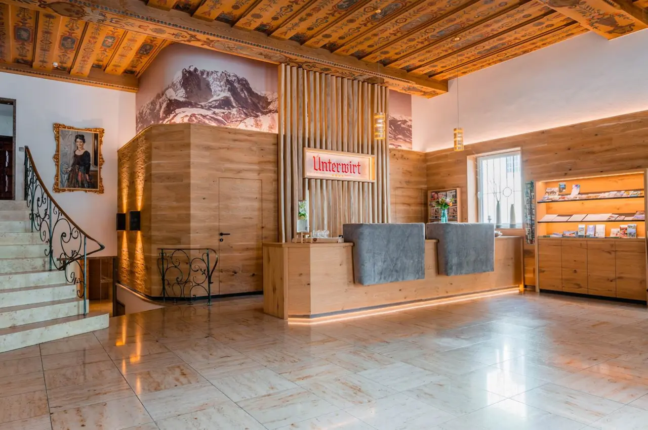 Empfangsbereich des Hotel Unterwirt mit traditioneller Holzvertäfelung, Bergbild und kunstvoller Deckenmalerei.