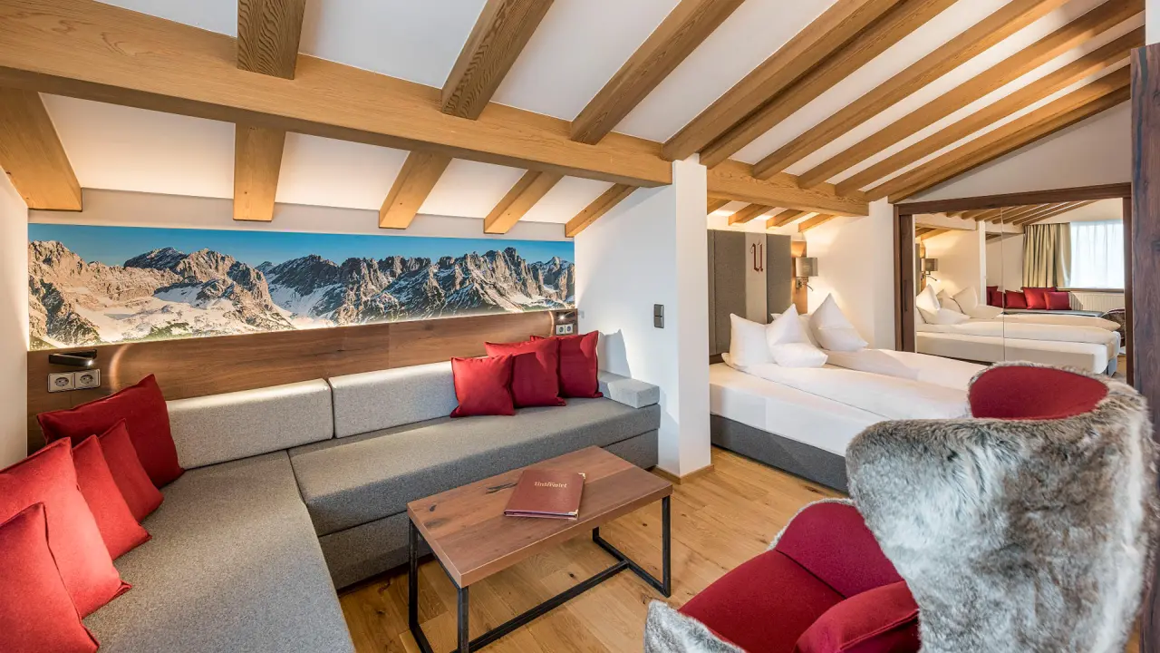 Gemütliche Suite im Hotel Unterwirt mit Wohnbereich, Schlafzimmer und Alpenpanorama-Wandbild. Ideal für entspannte Aufenthalte.