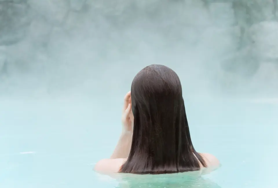 Person entspannt im dampfenden Thermalpool des DAS RONACHER Therme & Spa Resort