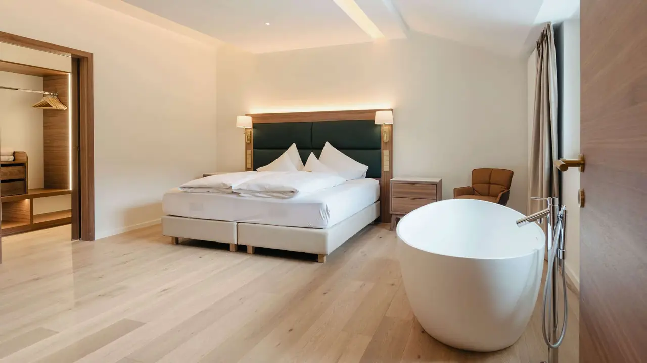 Geräumiges Hotelzimmer mit Doppelbett und freistehender Badewanne im DAS RONACHER Therme & Spa Resort.