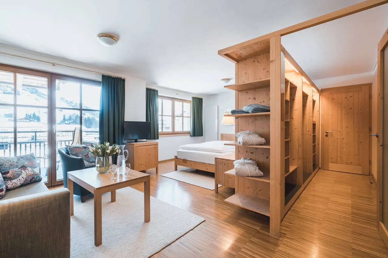 Gemütliches Hotelzimmer im Hotel Felbermayer mit Holzelementen, Balkon und Bergblick. Komfortable Einrichtung mit Bett und Sitzecke.