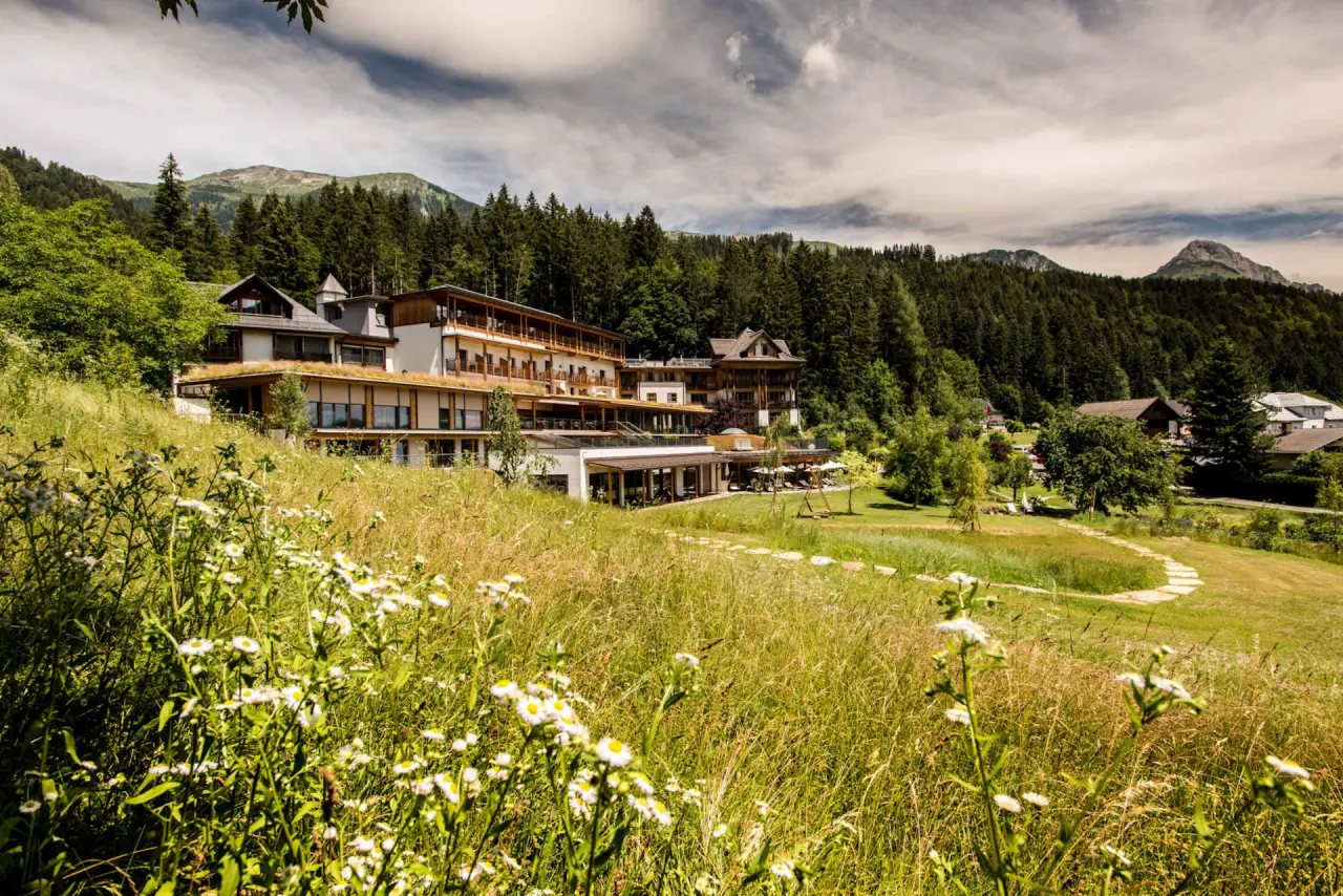 Aussenansicht des Biohotels der daberer eingebettet in grüne Wiesen und Wälder mit Bergpanorama.