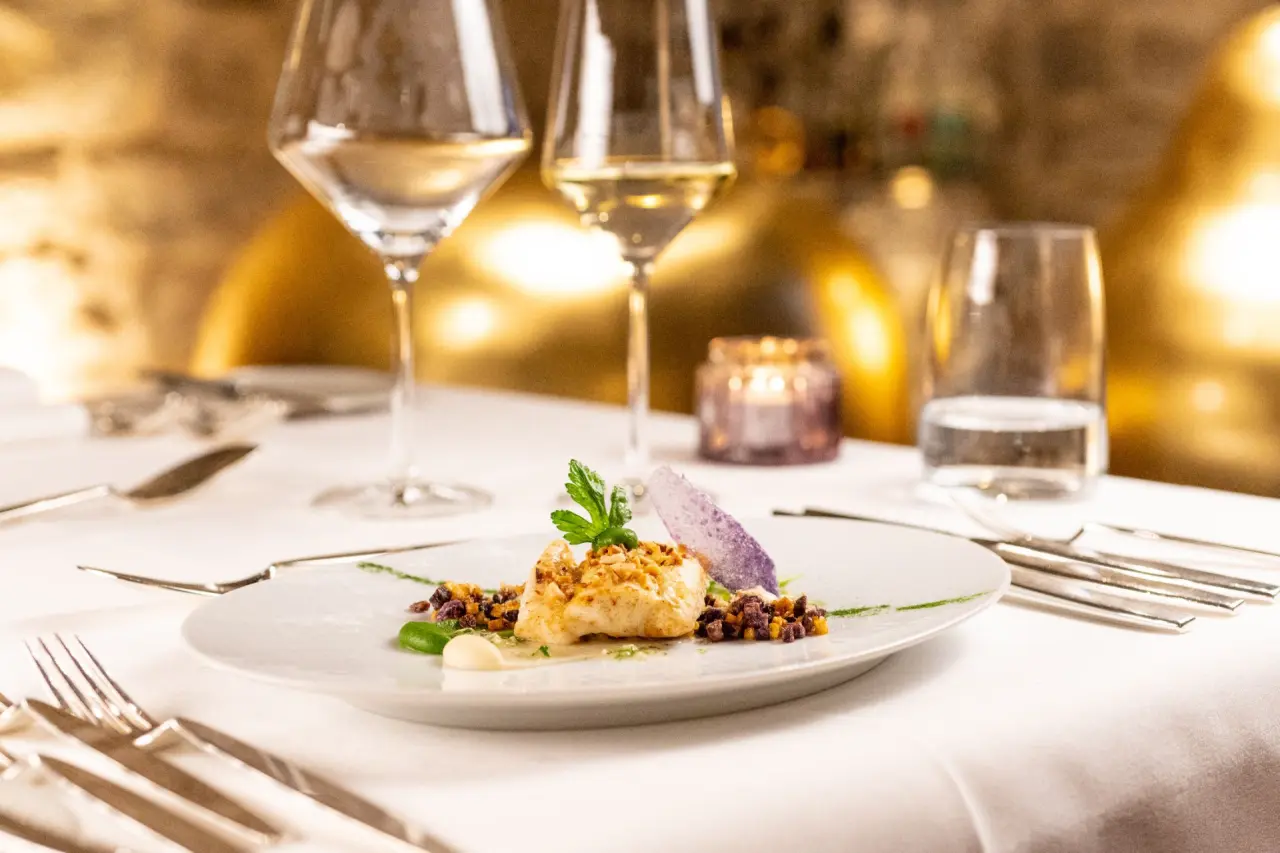 Exquisites Gourmetgericht mit Wein in elegantem Ambiente im Restaurant des BollAnts Spa im Park.