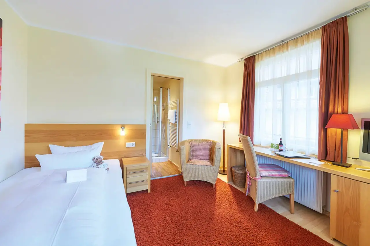 Gemütliches Hotelzimmer im BollAnts Spa im Park mit Doppelbett, Schreibtisch und Zugang zum Bad.