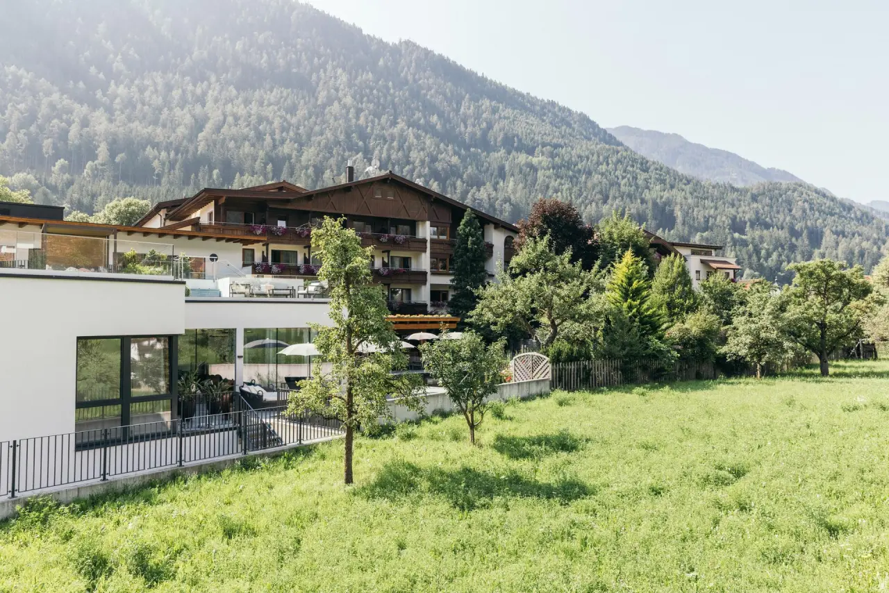 Aussenansicht des Gartenhotel Linde in den Bergen, umgeben von grünen Wiesen und Wäldern. Idyllische Lage für Wellness.