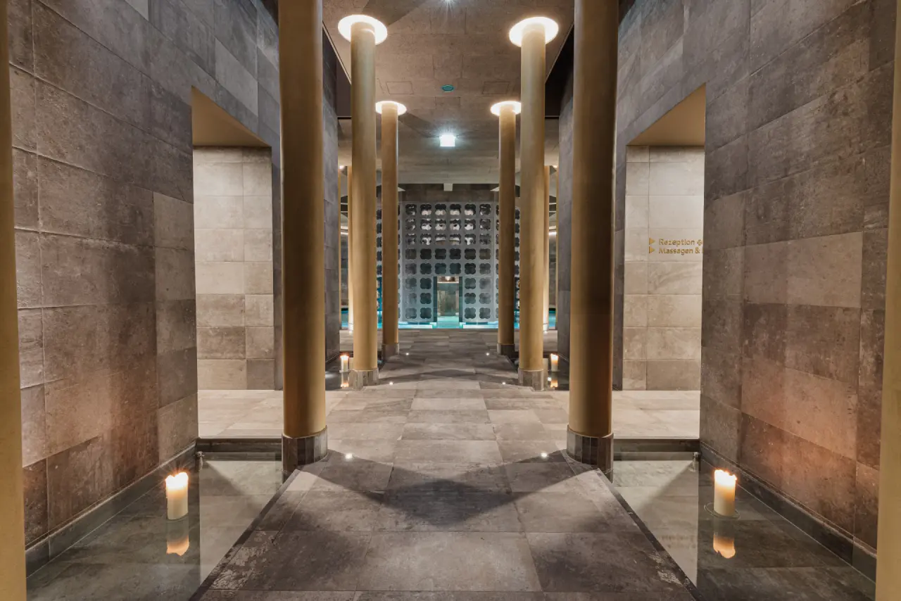 Eingangsbereich zum Silent Spa der Therme Laa mit Säulen, Kerzenlicht und Blick auf den Poolbereich.