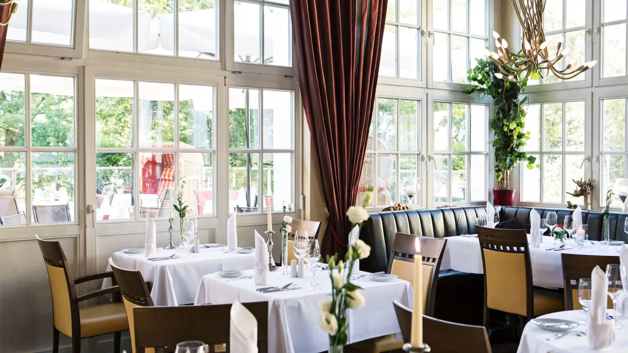 Helles Restaurant mit großen Fenstern und elegant gedeckten Tischen im Hotel Vier Jahreszeiten Kühlungsborn.