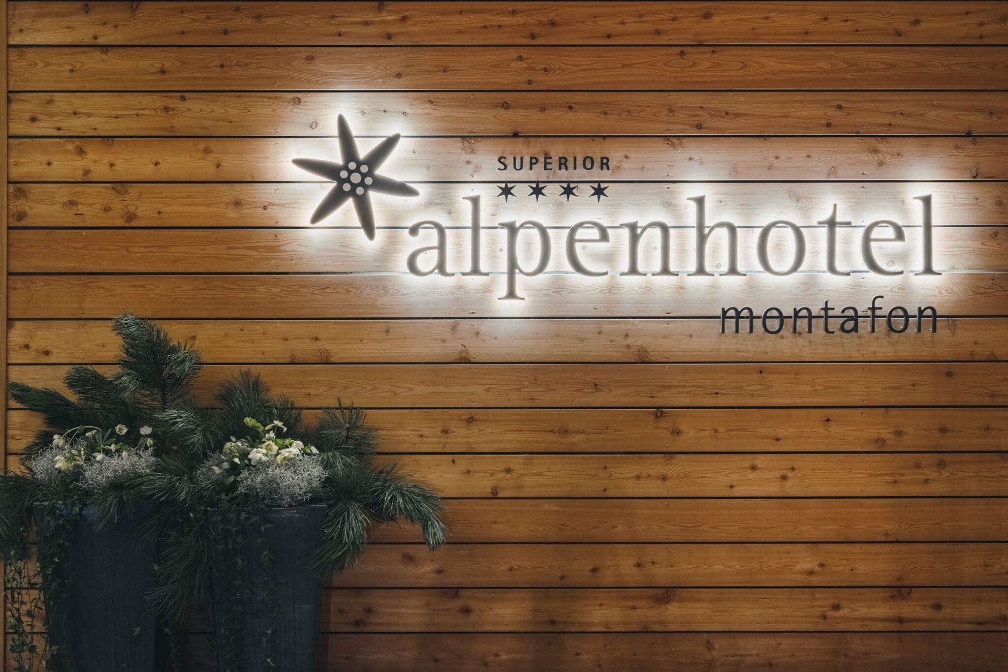 Alpenhotel Montafon in Schruns – Beleuchtetes Hotellogo an einer Holzwand | Wellnesshotel Montafon