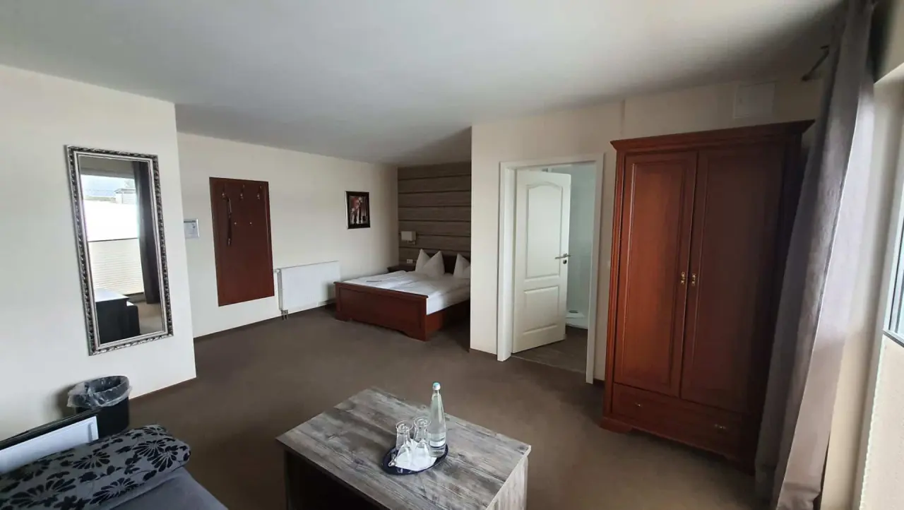 Gemütliches Doppelzimmer im Hotel Spreewaldhof Romantik mit Bett, Tisch und Blick ins Badezimmer.