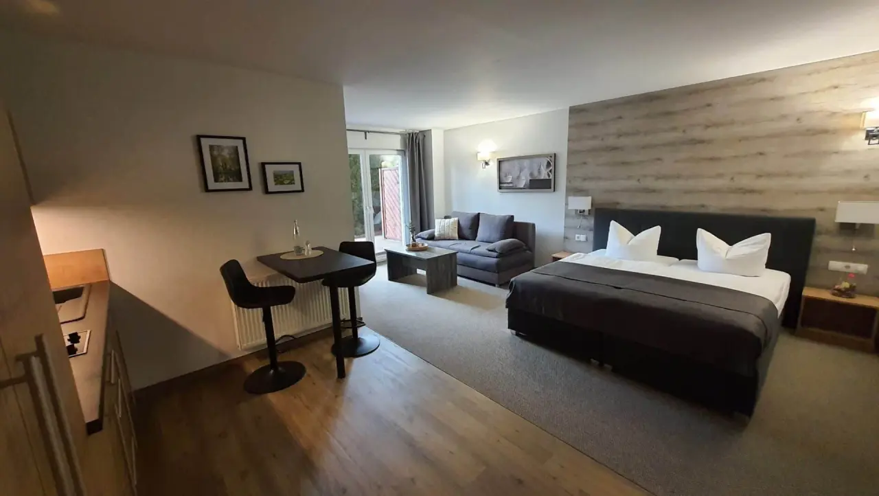 Gemütliches Doppelzimmer im Hotel Spreewaldhof Romantik mit großem Bett, Sofa, Esstisch und Zugang zur Terrasse.