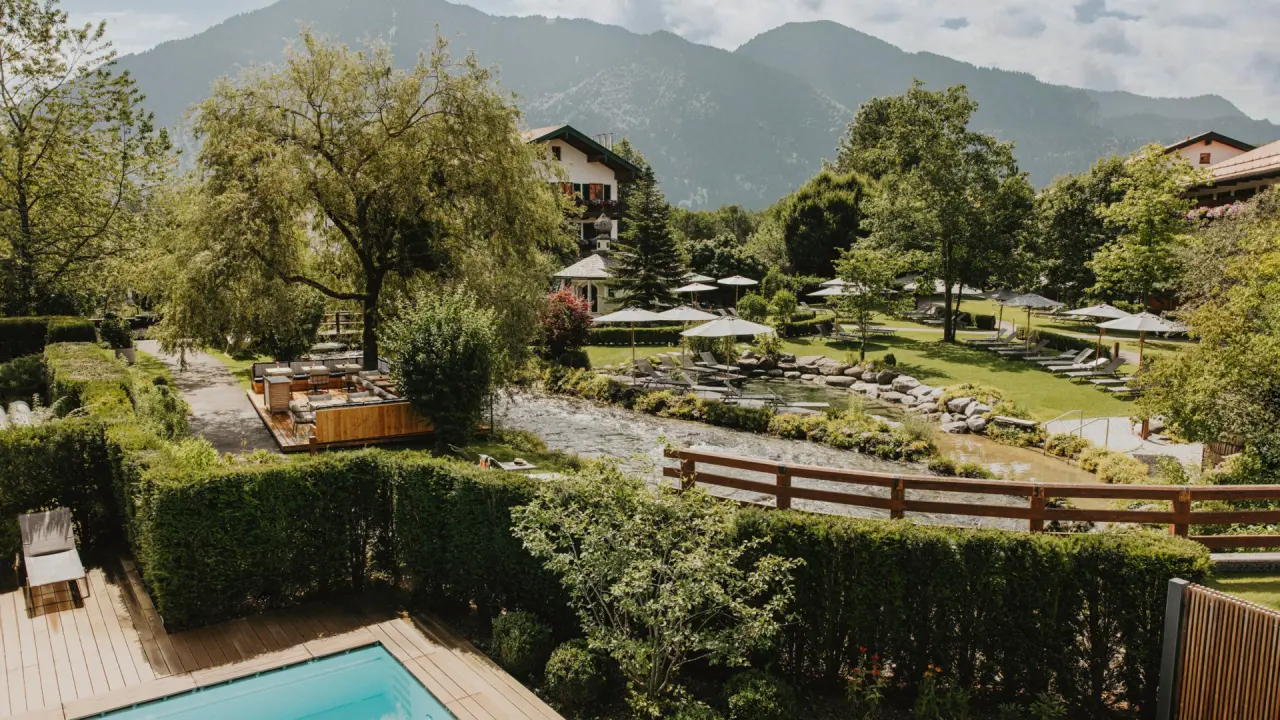 Weitläufiger Hotelgarten mit Aussenpool, Liegewiesen am Bach und Alpenpanorama im Bachmair Weissach Spa & Resort.
