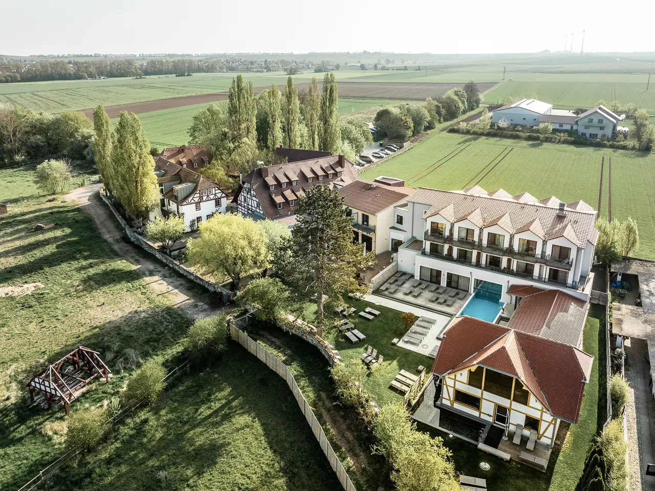 Luftaufnahme des Hotel Jordan's Untermühle mit Hotelanlage, Aussenpool und umliegenden Feldern.