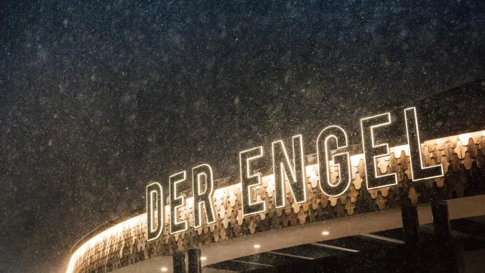 Beleuchtetes Hotel-Logo 'DER ENGEL' an der Fassade des Wellnesshotels Engel bei Schneefall.