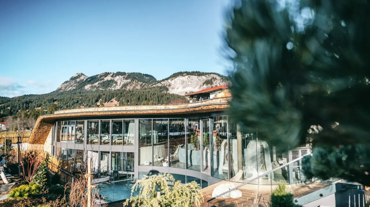 Modernes Wellnesshotel Engel mit Glasfassade, Spa-Bereich und Aussenpool vor alpiner Berglandschaft.