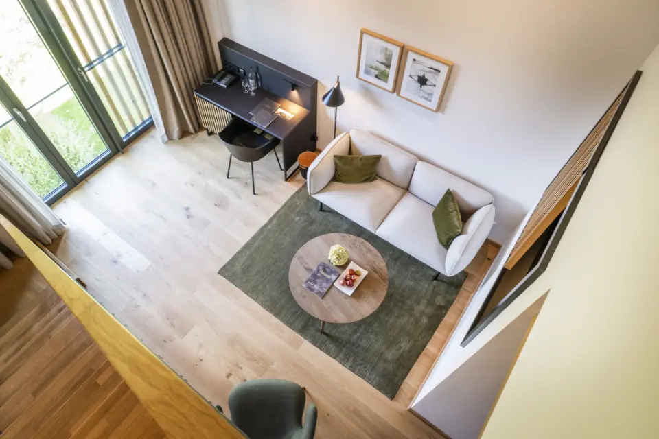 Modern eingerichteter Wohnbereich einer Suite im Hotel Breitenburg mit Sofa, Schreibtisch und Blick ins Grüne.