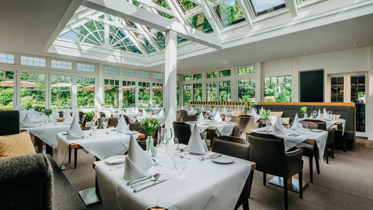 Helles Restaurant mit grossen Fenstern und Blick ins Grüne im Romantik Hotel Jagdhaus Eiden.